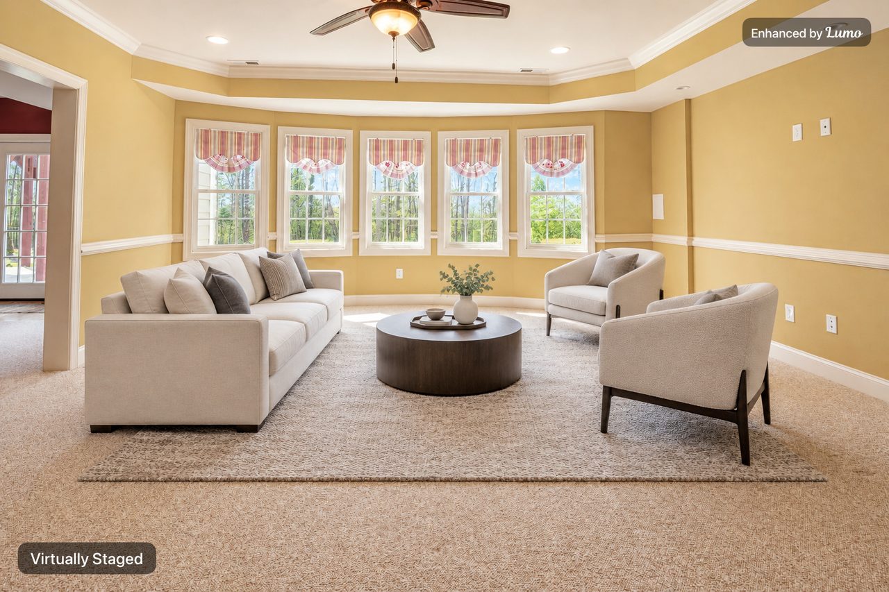 The same living room virtually staged in the Modern style with a sofa, two armchairs, a rug and a round coffee table, labeled Virtually Staged
